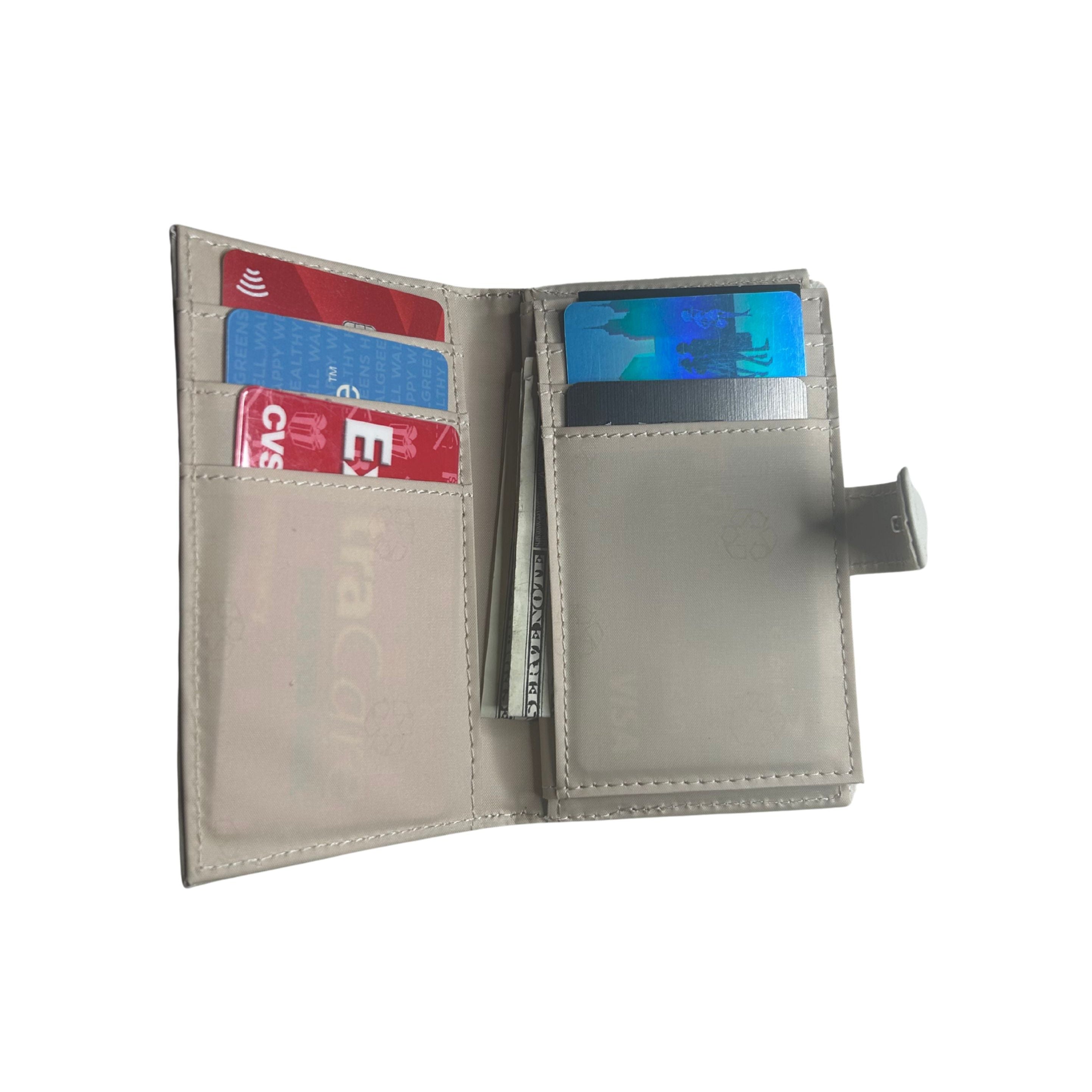 Interior view of the lambskin leather bifold wallet shown open, displaying its interior card slots, cash pocket, and a small side tab, with several sample credit cards inserted.