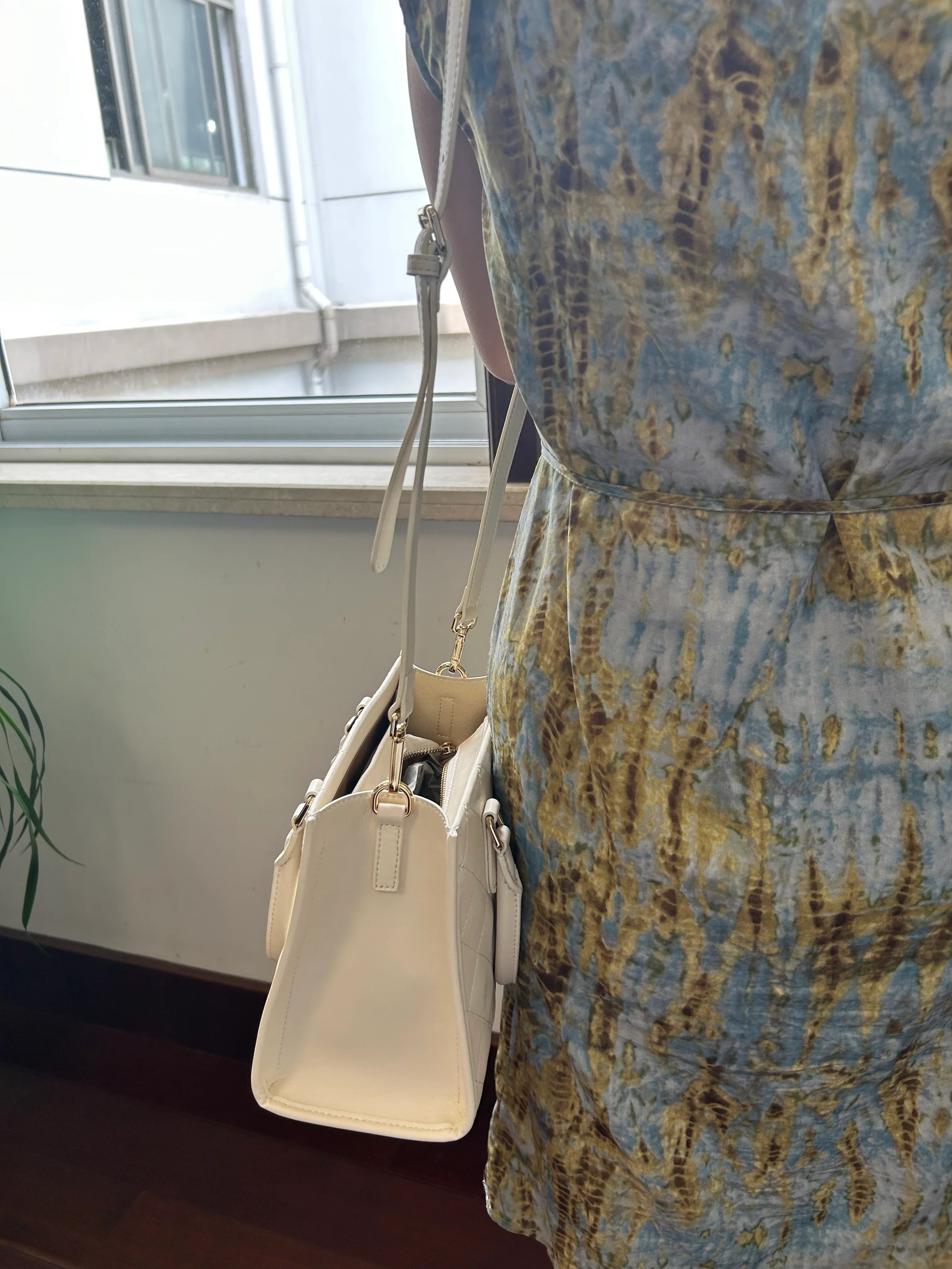 White quilted leather tote bag hanging with crossbody strap
