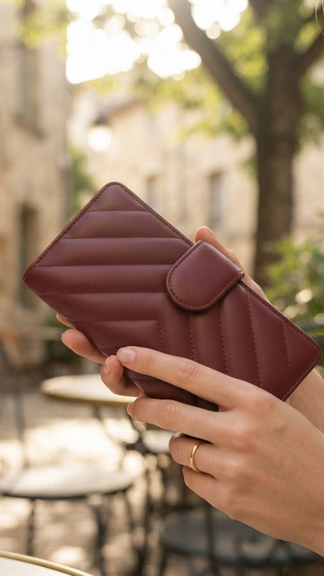 A woman holds a burgundy quilted lambskin leather wallet
