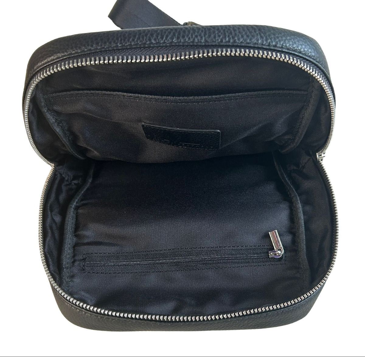 Black pebbled full-grain leather sling bag main compartment with zippered and slip pockets