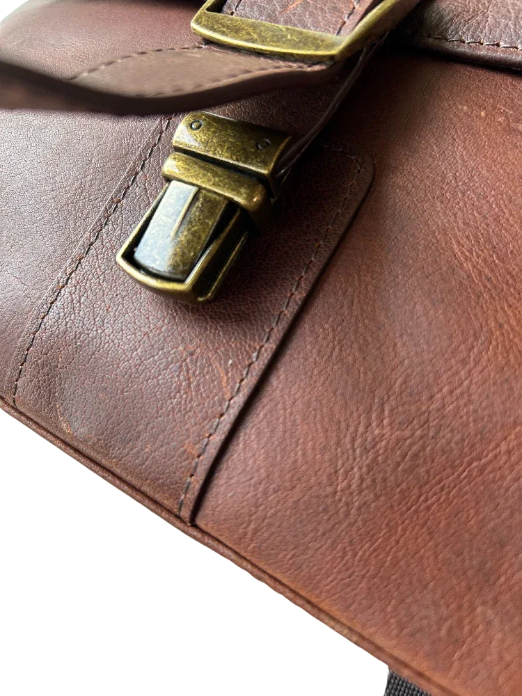 Close-up of leather buckle closure on Cambridge compact messenger bag