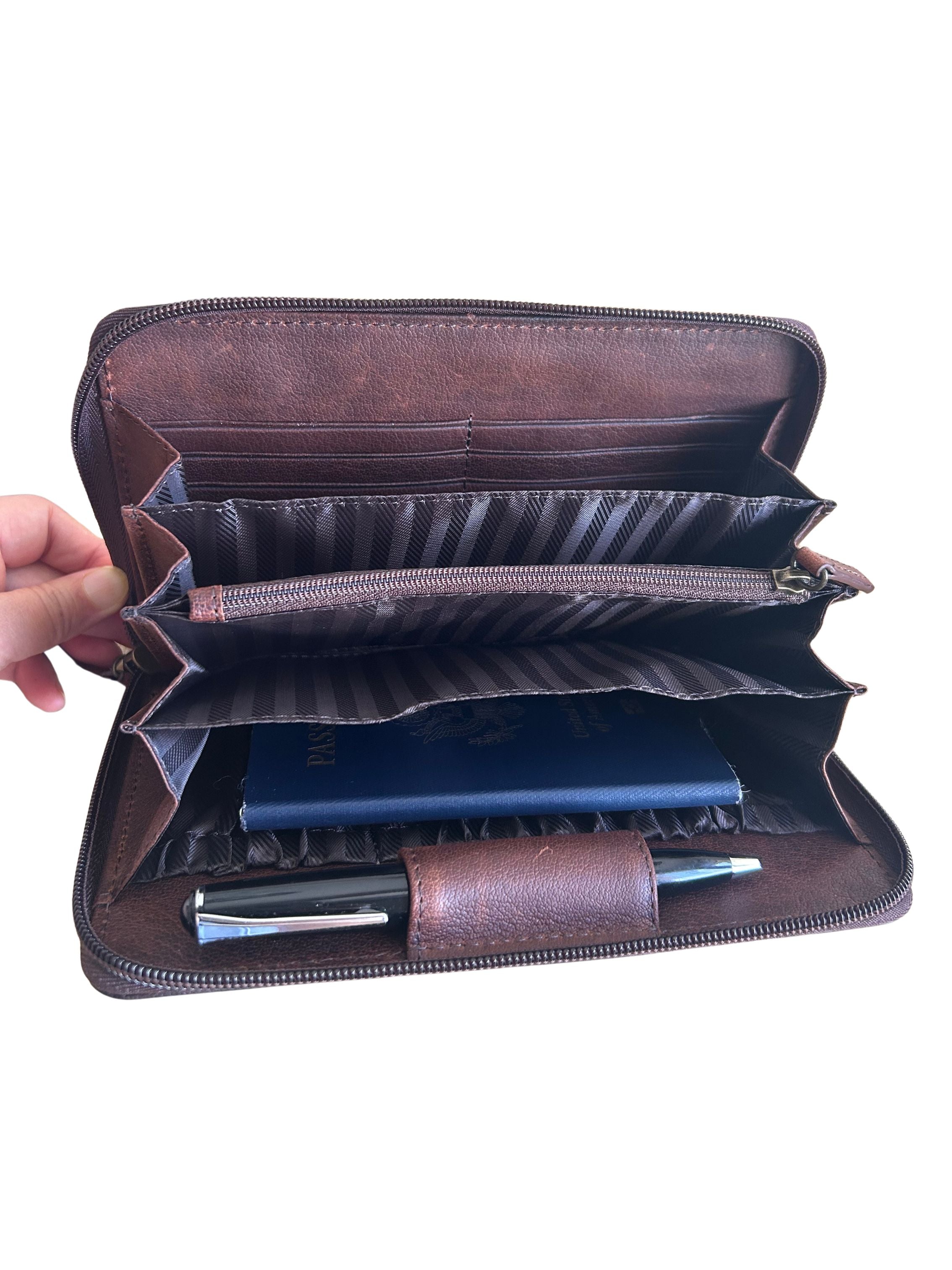 An open brown leather zip-around wallet  has multiple card slots, a zipper compartment, a striped divider, a pen loop, and a passport inside.