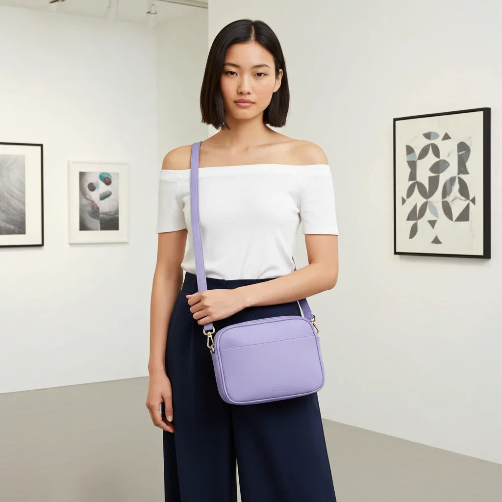 Woman carrying purple leather double-zip crossbody bag for everyday use