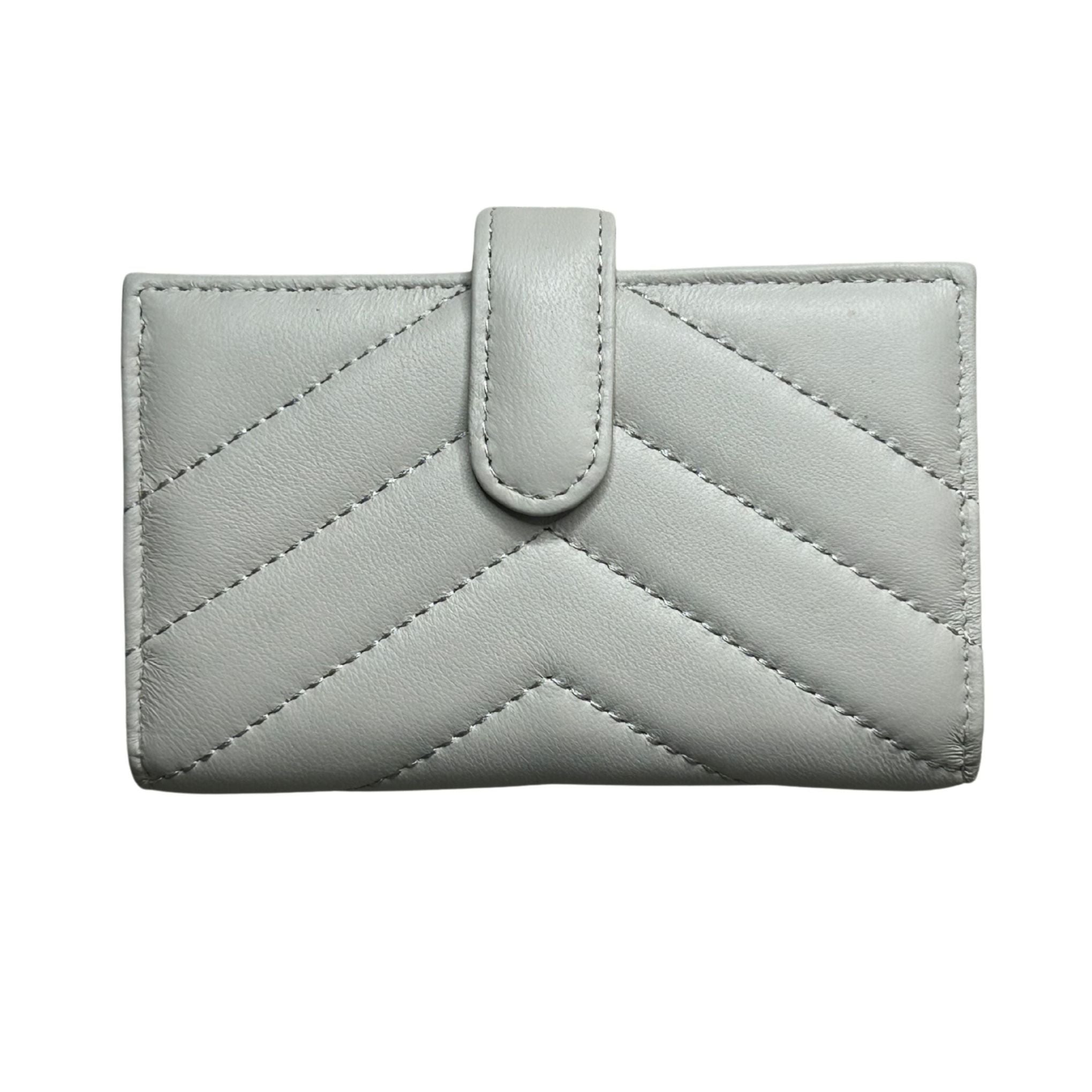 A white/ivory quilted lambskin leather wallet with a chevron pattern and a central tab closure